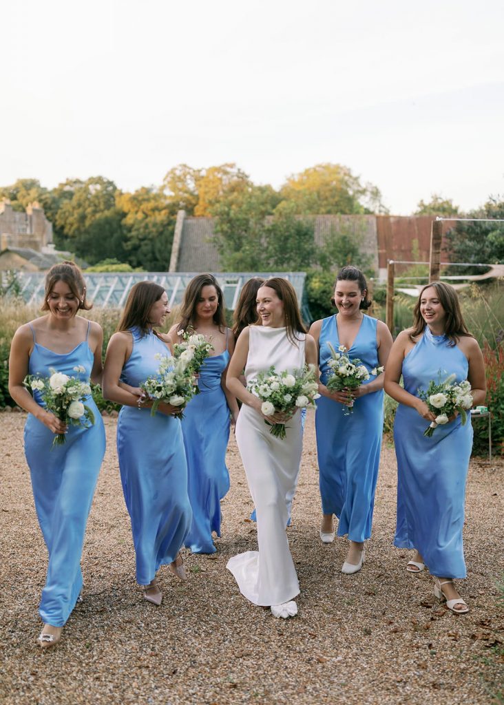 Bride walking with bridesmaids dressed in blue at Ripple Court Estate wedding in Kent