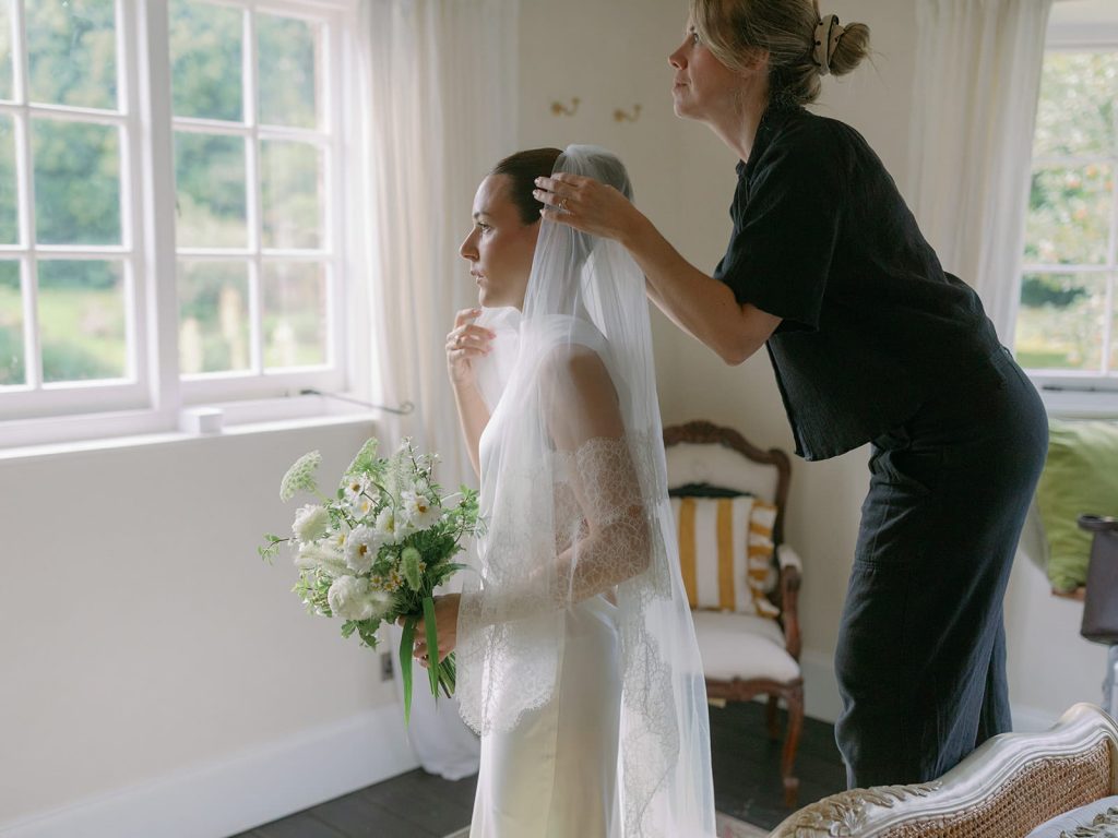 Bride having her veil adjusted while getting ready for wedding