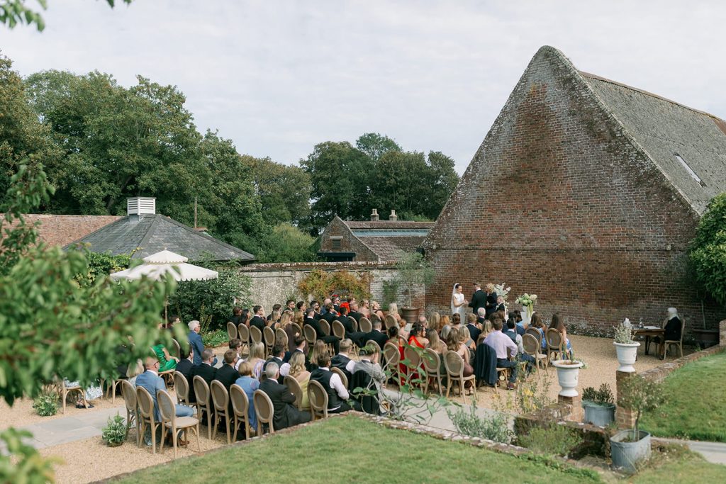 Outdoor wedding ceremony at Ripple Court Estate in Kent with guests seated in the courtyard