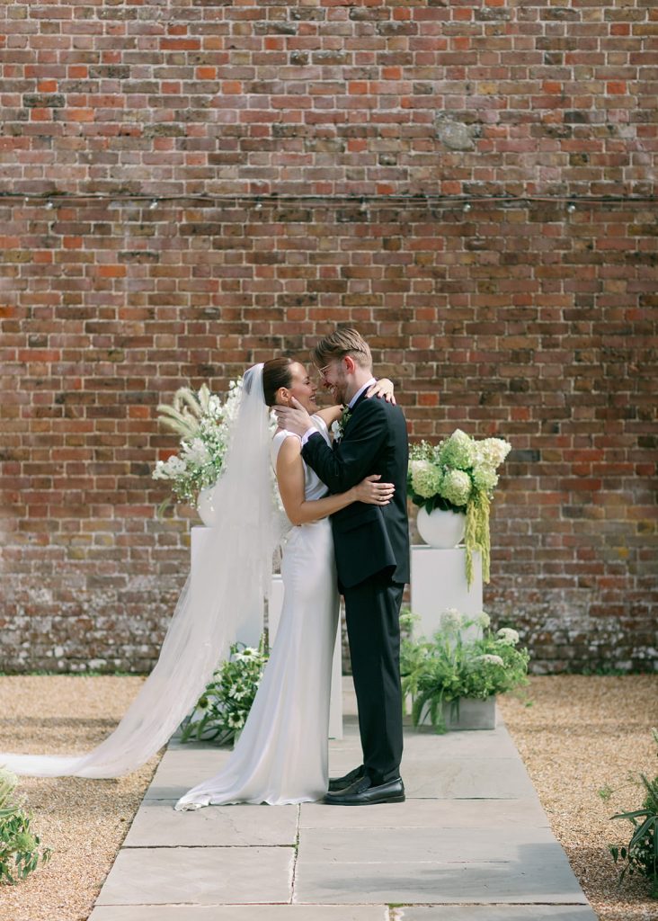 Bride and groom embracing during outdoor wedding ceremony at Ripple Court Estate in Kent