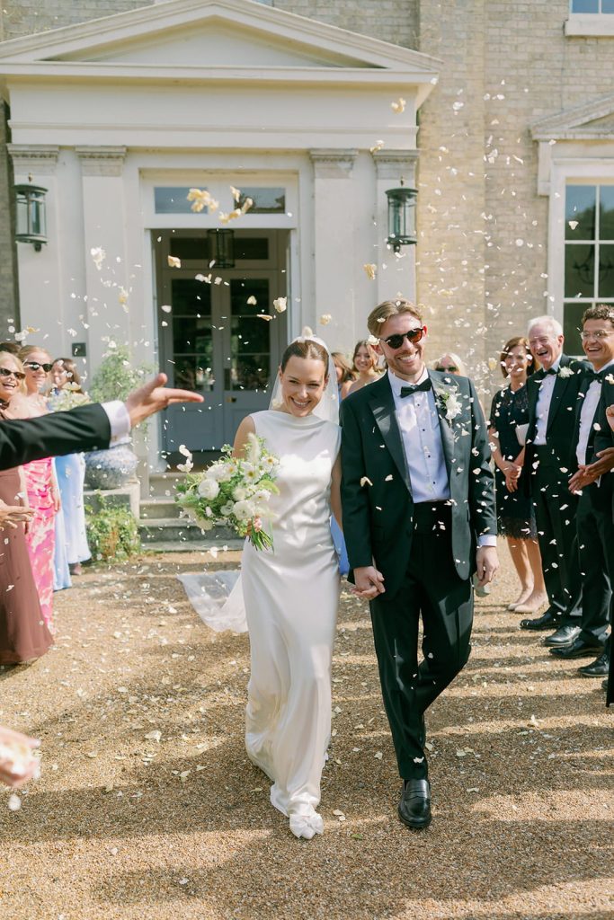 Bride and groom walking through confetti outside Ripple Court Estate in Kent