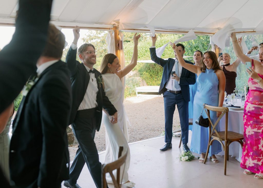 Bride and groom entering their wedding reception at Ripple Court Estate in Kent while guests wave napkins