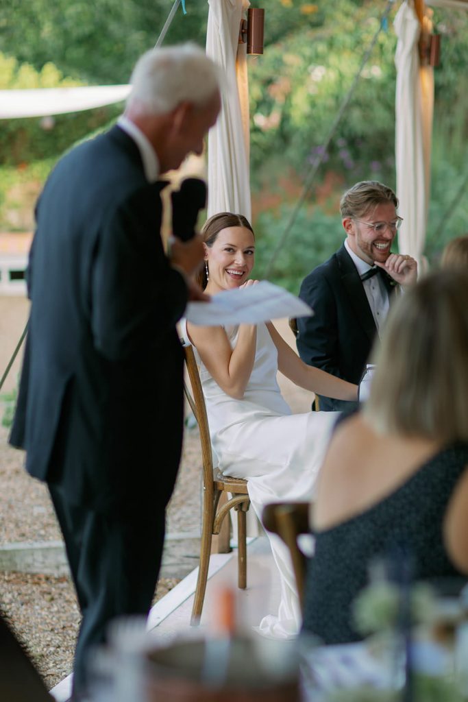 Bride and groom laughing during wedding speeches at Ripple Court Estate reception in Kent