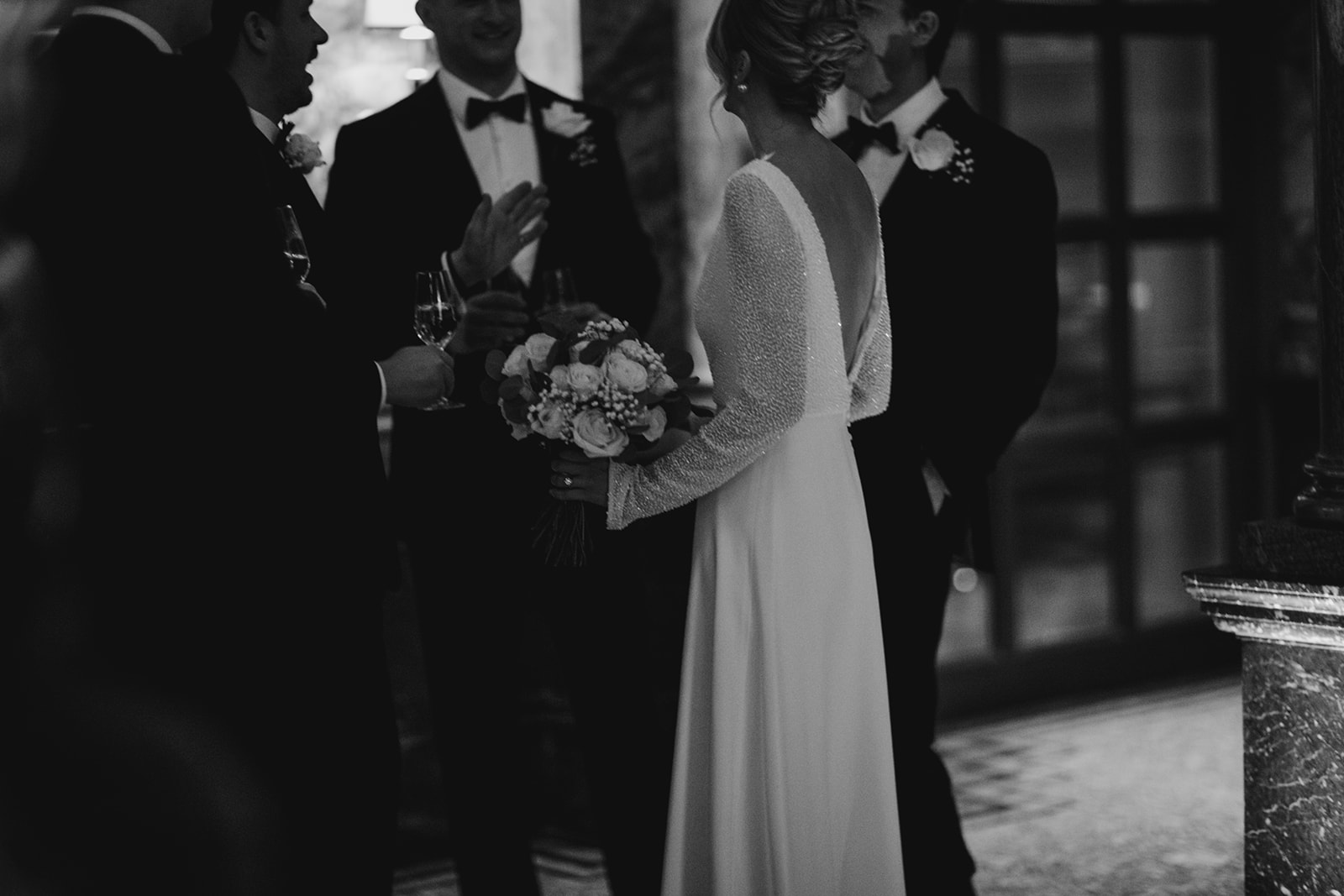 Bride greeting guests with champagne during wedding reception at Kimpton Fitzroy London with soft textured updo and natural bridal makeup