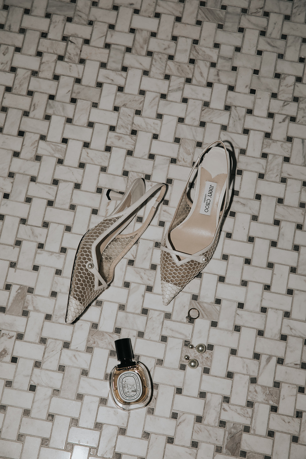 Bridal details with Jimmy Choo heels, perfume and accessories styled on marble floor for London wedding morning prep