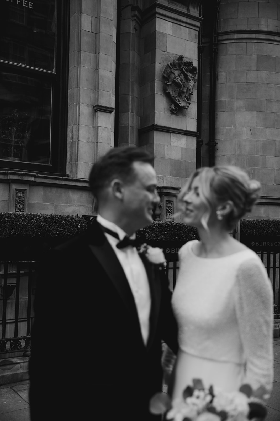 Bride and groom walking together outside London venue with bride wearing classic updo and soft glowy makeup